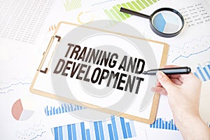 Text Training and Development on white paper sheet and marker on businessman hand on the diagram. Business concept