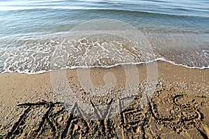 Text TRAVELS on the beach in summer