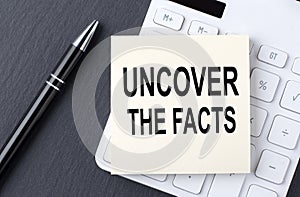 Text UNCOVER THE FACTS on sticker on the calculator, business concept