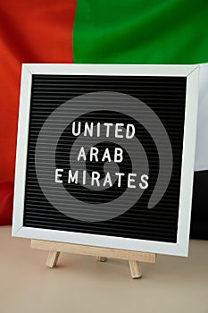 Text UNITED ARAB EMIRATES on background waving flag of UAE. National holiday, Independence Commemoration Day Muslim