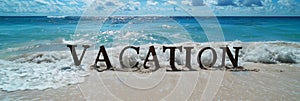 text vacation written on a sandy tropical beach, panoramic banner