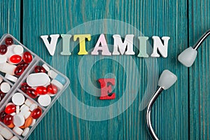 Text & x22;Vitamin E& x22; of colored wooden letters, stethoscope and pills