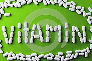 text - vitamins - of white pills, tablets on a green background, around pilule.