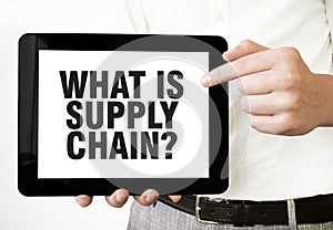 Text WHAT IS SUPPLY CHAIN on tablet display in businessman hands on the white background. Business concept