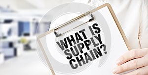 Text WHAT IS SUPPLY CHAIN on white paper plate in businessman hands in office. Business concept