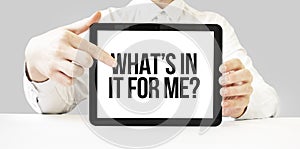 Text WHATS IN IT FOR ME on tablet display in businessman hands on the white bakcground. Business concept photo