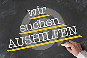 Text WIR SUCHEN AUSHILFEN, German for Help Wanted, written on blackboard photo