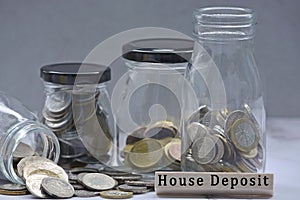 Text on wood block and glass jars with multicurrency coins. Blurred background