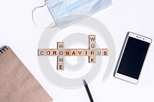 Text from wooden letters coronavirus work from home. Office supplies, a calculator, paper Notepad, a telphone, a pencil and a