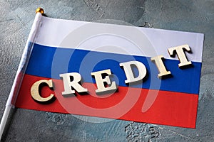 Text from wooden letters and the Russian flag on an abstract background, concept on the topic of using credit in Russia