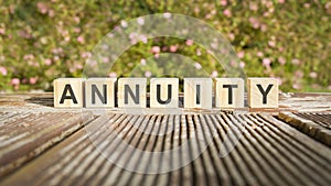 text of the word annuity on wooden cubes. flowers in the background