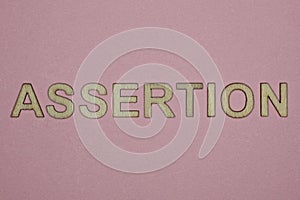 Text the word assertion from gray wooden small letters