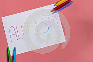 Text word autism on paper sheet written by colorful letter, on blue background.