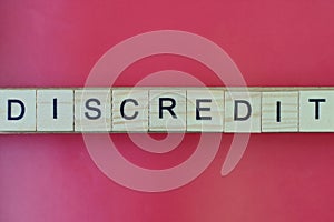Text the word discredit from gray wooden small letters