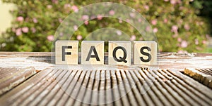 Text of the word FAQS on wooden cubes. flowers in the background
