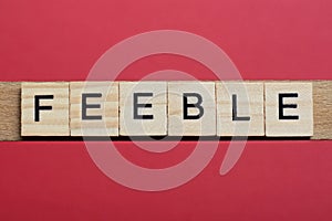 Text the word feeble from gray wooden small letters photo