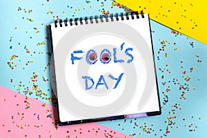 Text word Fool's day on scketchbook with funny eyes and confetti at background. 1 april message handwritting on