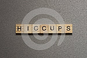 Text the word hiccups from brown wooden small letters
