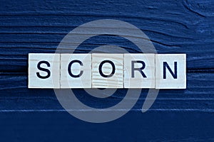 text the word scorn from brown wooden small letters