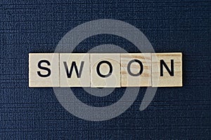 text on word swoon from gray wooden letters photo