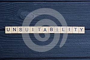 text the word unsuitability from brown wooden small letters