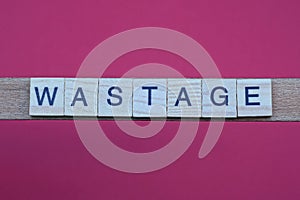 Text the word wastage from gray wooden small letters