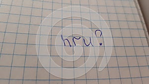 Text written in blue pen in a notebook - hru, which means the question, how are you.
