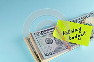Text written note Holiday budget, dollars cash money in rubber band with note, on copy space background - concept of financial