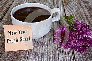 Text written on sticky note with white coffee cup - New year fresh start