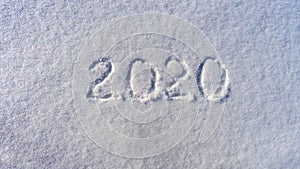 Text 2020 written on white fresh snow in sunny winter day. Merry Christmas and Happy New Year. Winter holiday concept
