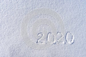 Text 2020 written on white fresh snow in sunny winter day. Merry Christmas and Happy New Year. Winter holiday concept