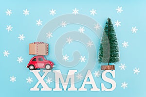 Text xmas and gift box on small red car, christmas tree, snowflakes. Concept holiday delivery gifts or purchases. Top view Flat la
