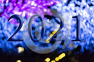 Text with the year number 2021 with a background of bright blue lights out of focus with Bokeh effect