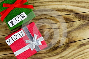 The text `For You` placed on a wooden background next to two .. colorful gift boxes