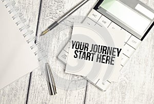 Text your journey start here on paper card and calculator on wooden background