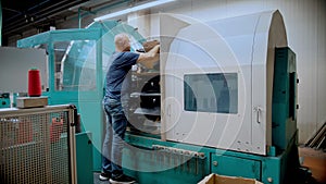 Textile factory worker works with thread coloring machine. Modern technology in dyeing yarns with machines for textile