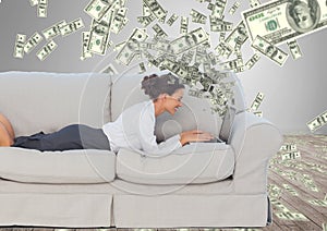 texting money. happy young woman on the sofa with laptop. Money coming up from laptop. photo