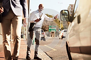 Texting the office that he is on his way. a handsome young businessman hailing a ride in the city.