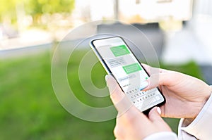 Texting sms with phone in city outdoor park. Woman sending text message with cellphone. Chatting on instant messaging app.