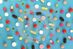 Texture from different medicines, tablets and capsules on a blue background.