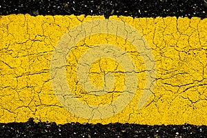 Texture of asphalt road with yellow line background, pattern of old cracked yellow painted on asphalt surface