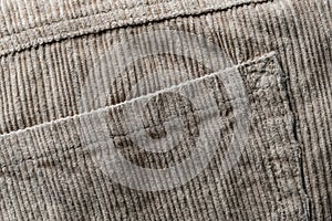Texture backdrop of beige colored corduroy fabric cloth with pocket . Corduroy retro fabric background or texture. Closeup view