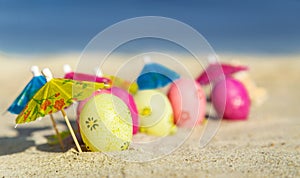 Texture (background) with colorful easter eggs with umbrellas on the beach with sea.