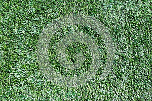 Texture on the background of a green artificial grass cover for stadiums and grounds. A plastic product for ennobling the territor