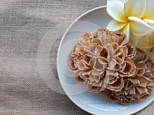 Texture background of Thai snacks name "kanom dork jork" on a dish with flowers. Space for text