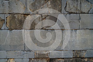 Texture background of weathered old natural stone brick wall in light grey with joint and rough surface