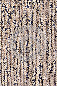 Texture of a beige mat with black spots fabric. Background of beige carpet with brown abstract spots