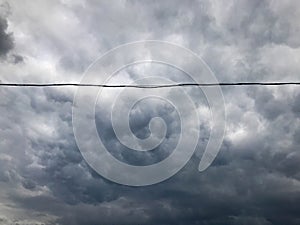 Texture of black tensioned high-voltage wires for electricity against a background of dark blue sullen stormy sky with rain clouds