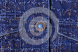 Texture of blue denim with gold threads. Beautiful blue button, pockets
