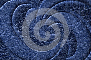 Texture of blue genuine leather close-up, with embossed twirl curve, spiral, trend pattern. Fashionable background, for
